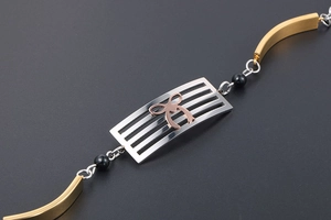 Macro detail of tricolor titanium steel bracelet with rose gold bow and black beads