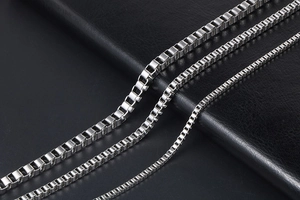 Polished silver box chains in three different widths on a black leather background