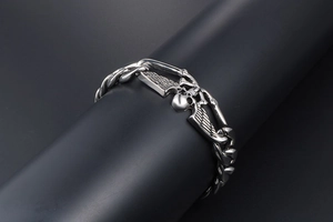 Détail macro du bracelet motard argenté avec crâne et ailes sur chaîne maille gourmette