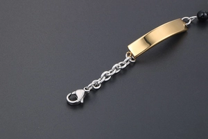 Detailed close-up of a polished gold-plated plaque bracelet with black beads and lobster clasp