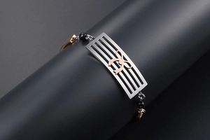 Detail of a stainless steel bracelet with a rose gold bow on a silver hollow plate