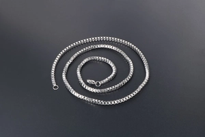 Close-up of a polished silver stainless steel box chain necklace with a lobster clasp