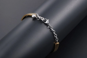 Close-up of dual-tone metal bracelet showing lobster clasp and silver bead detail