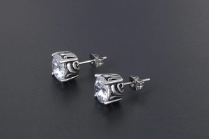 Detail of vintage silver earrings featuring scroll patterns and four-prong white zircon