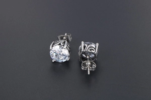 Detailed side view of vintage silver steel stud earrings with filigree engraving and crystals