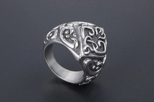 Close-up of vintage embossed titanium steel ring with scroll patterns and gothic motifs