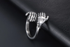 Macro shot of vintage silver skeleton hands clasping on punk stainless steel ring