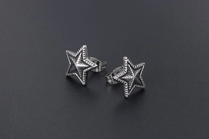 Macro shot of retro star stud earrings in silver steel with radial texture and butterfly back