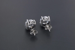 Close-up of vintage silver stud earrings with round zircons and engraved hollow patterns