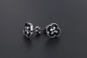 Close-up of silver steel stud earrings featuring black gothic cross relief pattern
