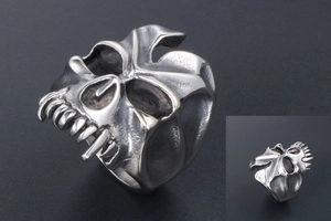 Close-up of vintage monster skull ring with exaggerated long fangs and distressed silver finish