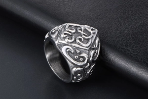 Detailed close-up of retro engraved floral patterns on a wide stainless steel band ring