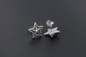 Detailed close-up of silver star stud earrings with radial texture and butterfly backs