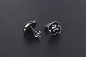 Detail of silver titanium steel cross earrings with black enamel punk gothic style
