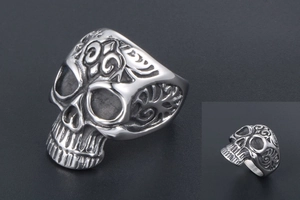 Detail of vintage punk skull ring with fleur-de-lis engraving and oxidized finish