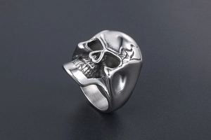 Détail macro d'une bague tête de mort gothique en acier argenté avec finitions vieillies