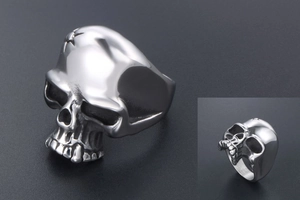 Detailed close-up of a punk skull ring in polished stainless steel with blackened accents