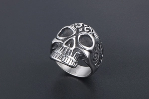 Detail of vintage skull ring with intricate relief engraving and gothic scroll textures