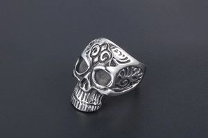 Detailed macro view of vintage skull ring with embossed floral relief and blackened finish