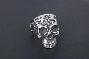 Detailed close-up of retro stainless steel skull ring with embossed floral patterns
