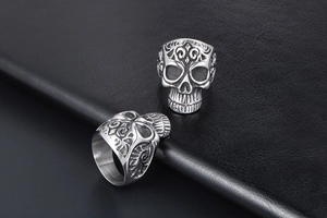 Macro shot of vintage skull ring with embossed floral patterns on black leather background