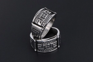 Macro detail of silver titanium steel ring with Greek meander pattern and textured mesh