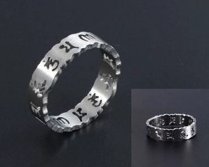 Détail de la bague en acier argenté avec texture brossée et gravures de mantras ajourées