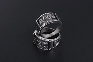 Detailed close-up of retro silver steel rings featuring embossed Greek meander pattern