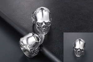 Detailed view of a silver gothic skull ring with intricate carving on black leather