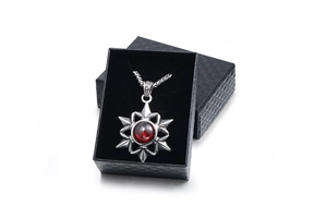 Octagonal star necklace with red gemstone displayed in a premium black jewelry box