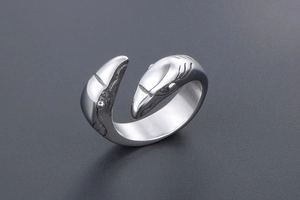 Macro shot of silver shark shaped open ring with detailed engraving on stainless steel