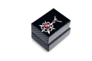 Macro view of vintage star necklace with red gemstone and black textured jewelry gift box