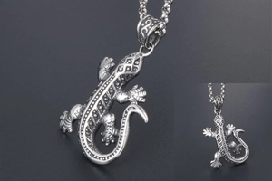 Détail d'un pendentif gecko argenté avec texture en relief et style punk rétro
