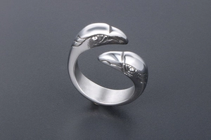 Detailed close-up of a stainless steel ring with dual eagle head engravings and open band