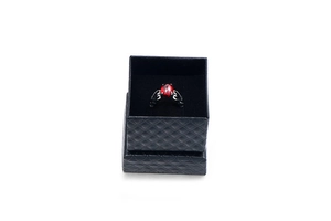 Gothic black alloy ring with oval red gemstone displayed in a black diamond-pattern box