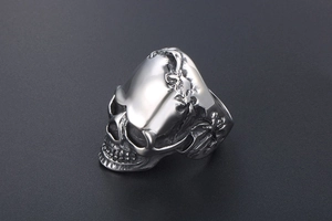 Detail of vintage steel skull ring featuring a carved lizard motif on a dark textured background
