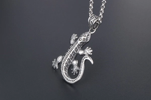 Vue détaillée du pendentif gecko argenté vintage avec motifs sur chaîne à billes en acier