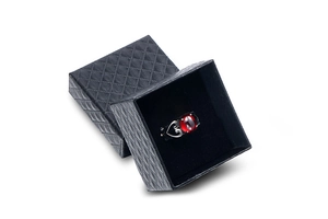 Detail of a vintage silver ring with red oval stone in a black quilted jewelry gift box