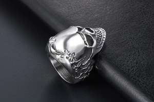 Macro detail of silver titanium skull ring with floral engraving on textured leather