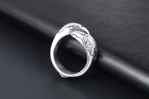 Macro detail of intertwined vintage eagle heads with intricate feather carvings on silver ring
