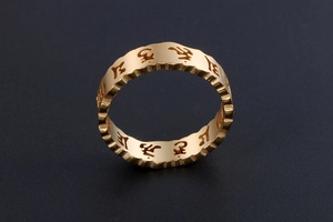 Détail macro de la bague mantra dorée avec bords ondulés et gravure religieuse