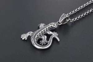Gros plan du pendentif lézard argenté montrant les écailles et la texture du métal vintage