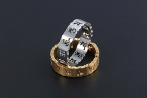 Macro de bagues or et argent avec gravures évidées du mantra bouddhiste de couple
