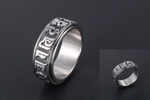 Macro shot of silver stainless steel spinner ring featuring engraved Buddhist mantras