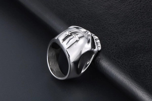 Close-up of embossed silver skull ring with crossed swords on black leather background