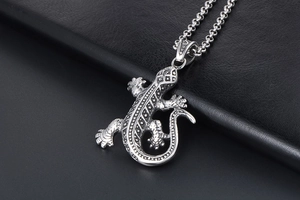 Vue macro du pendentif gecko argenté aux motifs tribaux sur fond de cuir noir