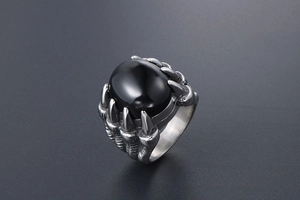 Détail d'une bague griffe de dragon argentée sertie d'une pierre noire ovale style vintage