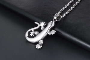 Détail d'un pendentif lézard gecko en argent sur une chaîne à maillons en acier