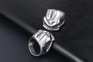 Detailed view of silver skull rings with embossed swords and fangs on black leather