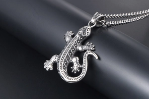 Détail d'un pendentif gecko vintage avec gravures géométriques sur une chaîne à billes